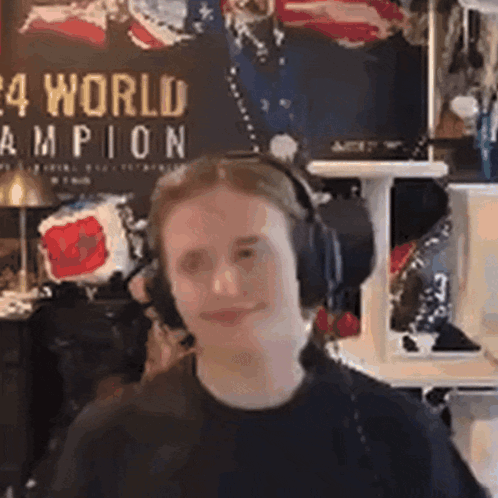 A Man Wearing Headphones Is Making A Funny Face In Front Of A Wall With A Poster On It . GIF