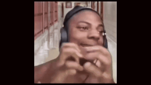a man wearing headphones is making a funny face while standing in a hallway .