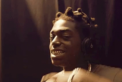 A Man Wearing Headphones Is Making A Funny Face While Touching His Teeth . GIF