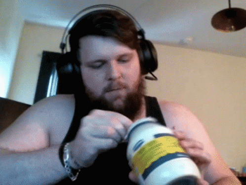 A Man Wearing Headphones Is Opening A Bottle Of Lotion GIF