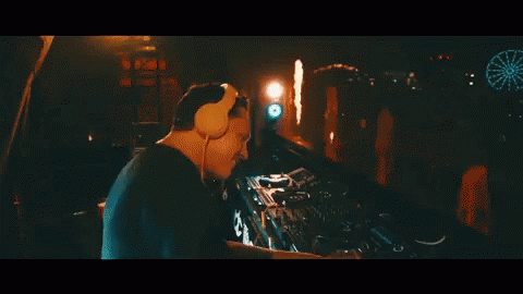 A Man Wearing Headphones Is Playing A Dj Set At A Party GIF