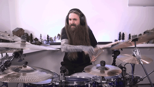 A Man Wearing Headphones Is Playing Drums GIF