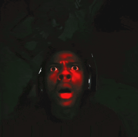 A Man Wearing Headphones Is Screaming With A Red Light Projected On His Face GIF