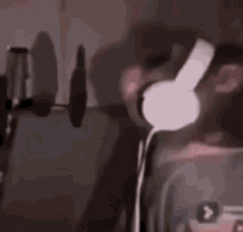 A Man Wearing Headphones Is Singing Into A Microphone In A Dark Room . GIF