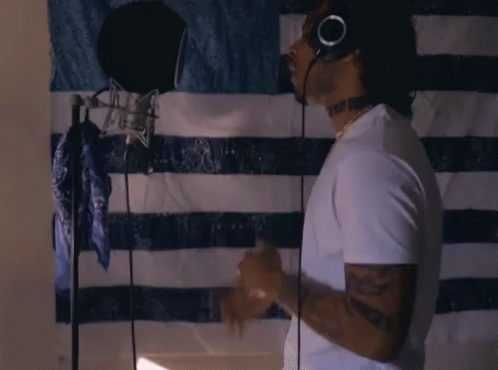 A Man Wearing Headphones Is Singing Into A Microphone GIF