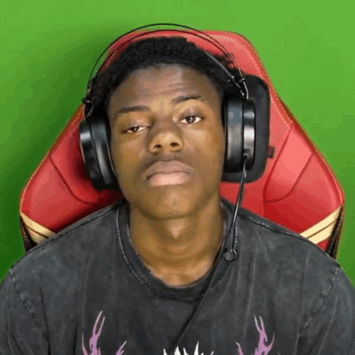 a man wearing headphones is sitting in a chair with a green background