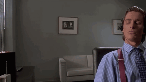 A Man Wearing Headphones Is Sitting In A Chair With His Eyes Closed . GIF