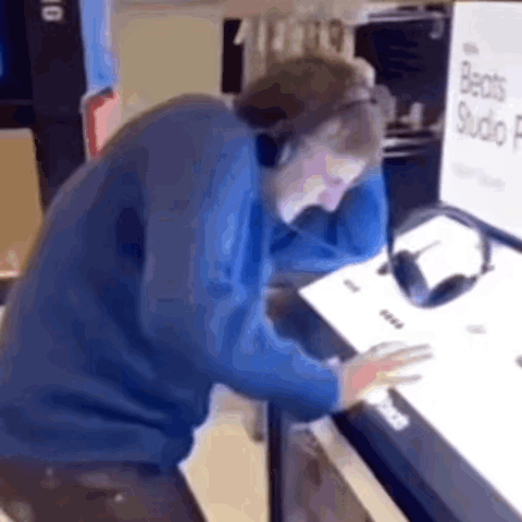 A Man Wearing Headphones Is Sitting In Front Of A Computer . GIF