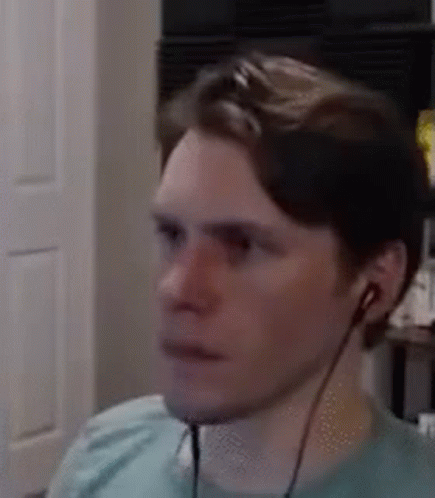 A Man Wearing Headphones Is Sitting In Front Of A Computer Monitor . GIF