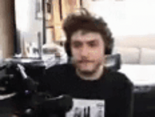 A Man Wearing Headphones Is Sitting In Front Of A Computer Screen . GIF