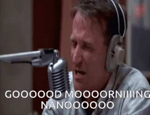 A Man Wearing Headphones Is Sitting In Front Of A Microphone And Saying Good Morning Nanooooo GIF
