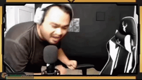 A Man Wearing Headphones Is Sitting In Front Of A Microphone In A Room . GIF