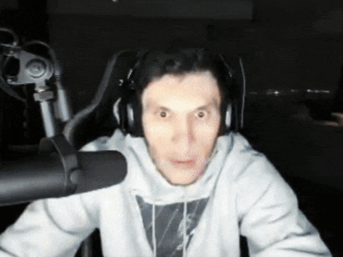 A Man Wearing Headphones Is Sitting In Front Of A Microphone Making A Funny Face GIF
