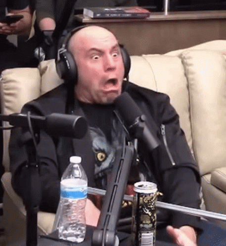 A Man Wearing Headphones Is Sitting In Front Of A Microphone With A Can Of Soda And A Bottle Of Water . GIF