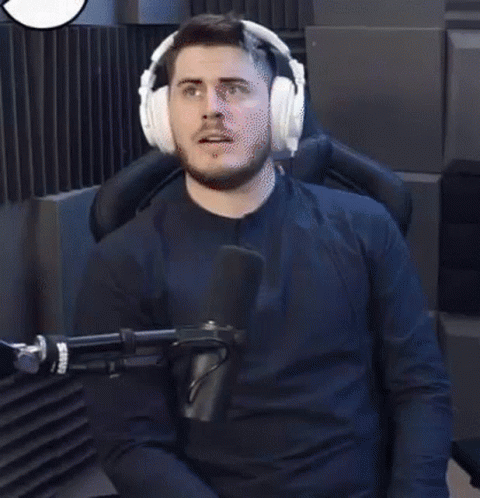 A Man Wearing Headphones Is Sitting In Front Of A Microphone With The Word Wasted In Red Letters Behind Him . GIF