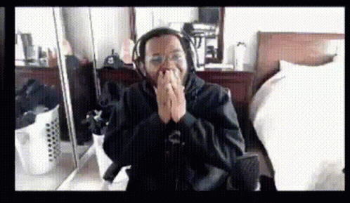 A Man Wearing Headphones Is Sitting In Front Of A Mirror With His Hands Folded GIF