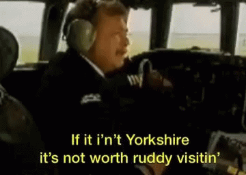 A Man Wearing Headphones Is Sitting In The Cockpit Of A Plane And Talking . GIF