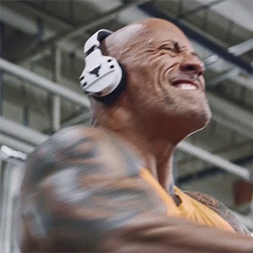 A Man Wearing Headphones Is Smiling And Dancing In A Gym GIF