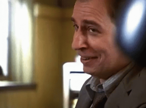 A Man Wearing Headphones Is Smiling And Looking At The Camera GIF