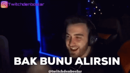 A Man Wearing Headphones Is Smiling And Pointing At The Camera In A Dark Room . GIF