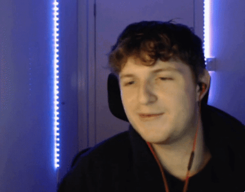 A Man Wearing Headphones Is Smiling In Front Of A Blue Wall GIF