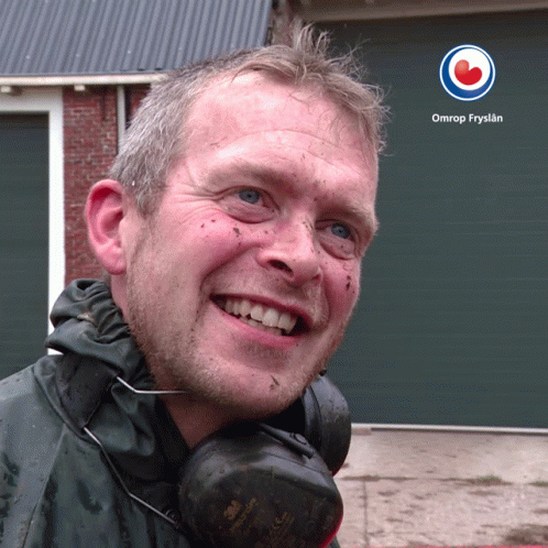 A Man Wearing Headphones Is Smiling In Front Of A Omrop Fryslan Logo GIF