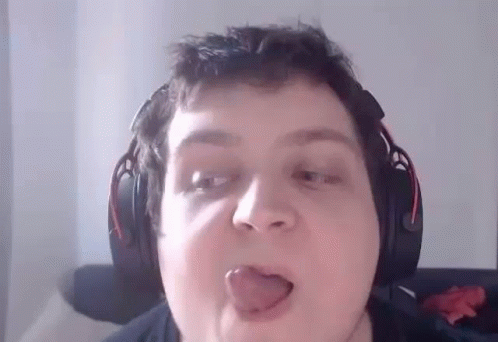 A Man Wearing Headphones Is Sticking His Tongue Out While Making A Funny Face . GIF