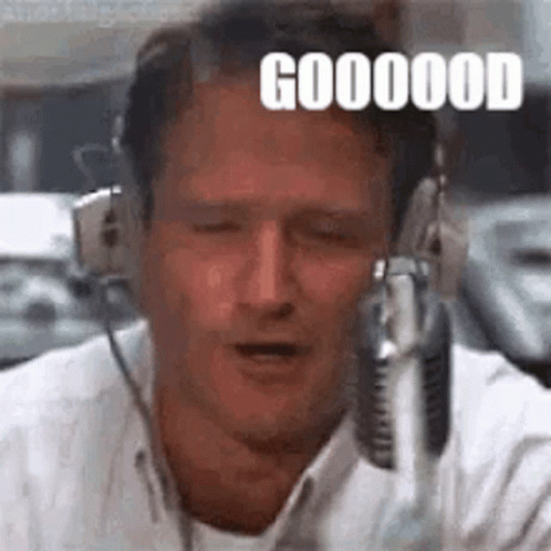 A Man Wearing Headphones Is Talking Into A Microphone And Making A Funny Face . GIF