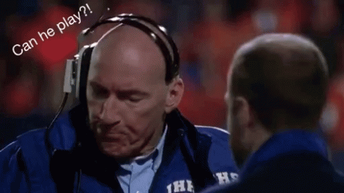 A Man Wearing Headphones Is Talking To Another Man On A Field . GIF