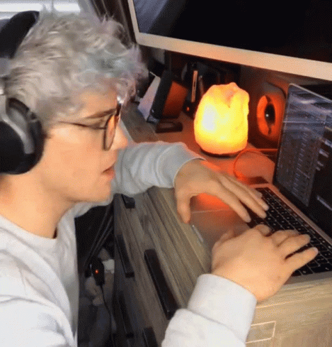 A Man Wearing Headphones Is Typing On His Laptop GIF