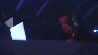 A Man Wearing Headphones Is Using A Laptop In A Dark Room GIF