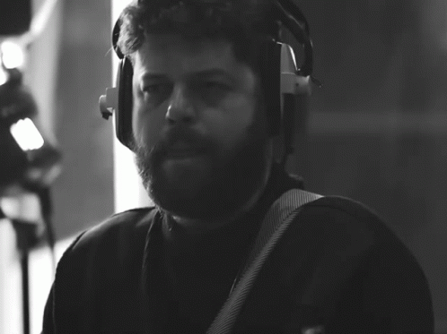 a man wearing headphones playing a guitar in a black and white photo