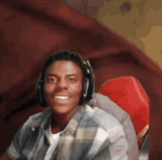 A Man Wearing Headphones Sits In A Red Chair GIF