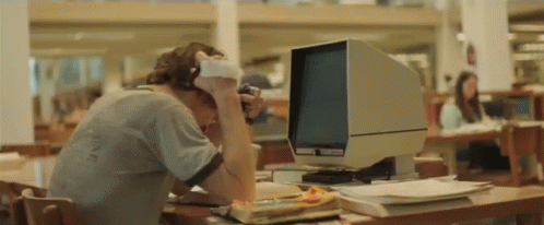 a man wearing headphones sits in front of a computer monitor