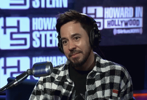A Man Wearing Headphones Stands In Front Of A Howard J Hollywood Sign GIF