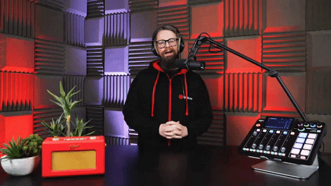 A Man Wearing Headphones Stands In Front Of A Microphone And Mixer GIF