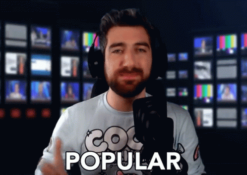 A Man Wearing Headphones Stands In Front Of A Microphone With The Word Popular On His Shirt GIF
