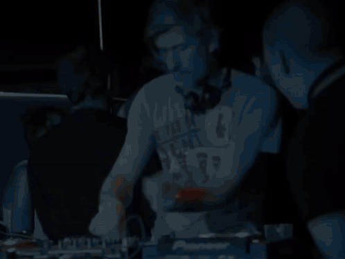A Man Wearing Headphones Stands In Front Of A Pioneer Dj Controller GIF