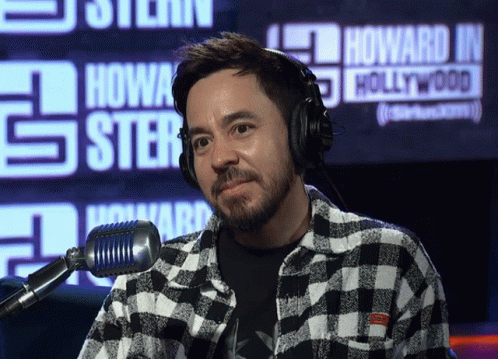 A Man Wearing Headphones Stands In Front Of A Sign That Says Howard J. Hollywood GIF