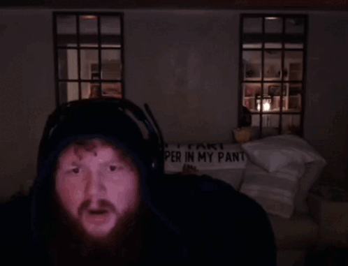 A Man Wearing Headphones Stands In Front Of A Sign That Says " Part Per In My Pant " GIF