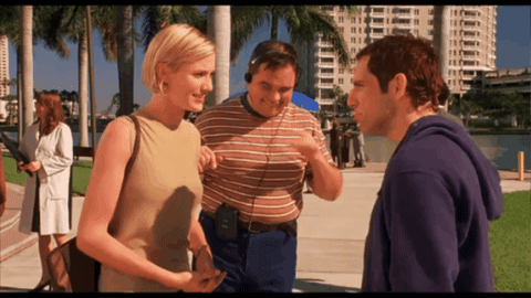 A Man Wearing Headphones Talks To Two Women GIF