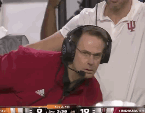 A Man Wearing Headphones Watches A Football Game Between Indiana And Iowa GIF