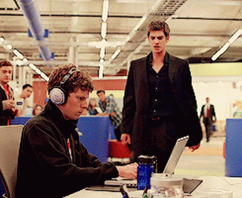 A Man Wearing Headphones Works On A Laptop GIF