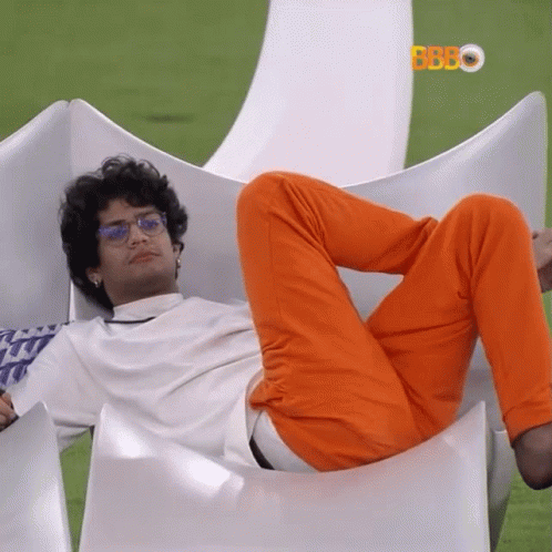 Man In Orange Pants And Glasses Laying On White Chair GIF