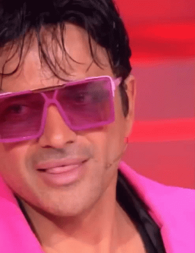 a man wearing pink sunglasses and a pink jacket smiles