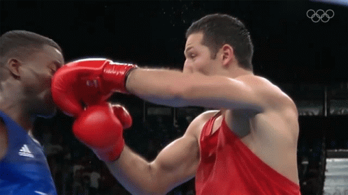 A Man Wearing Red Boxing Gloves Punches Another Man In A Blue Tank Top GIF