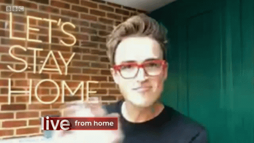 A Man Wearing Red Glasses Stands In Front Of A Brick Wall With The Words Let 'S Stay Home Live From Home GIF