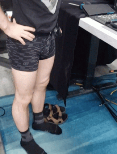 A Man Wearing Shorts And Socks Stands On A Blue Rug GIF