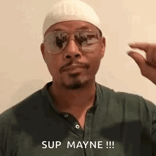 A Man Wearing Sunglasses , A Hat And A Green Shirt Is Holding A Pill In His Hand . GIF