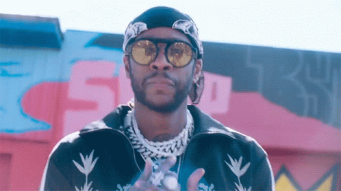 A Man Wearing Sunglasses And A Bandana Is Standing In Front Of A Wall With The Number 5 On It GIF